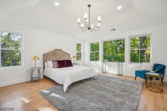 bedroom with lofted ceiling, hardwood / wood-style floors, and a notable chandelier