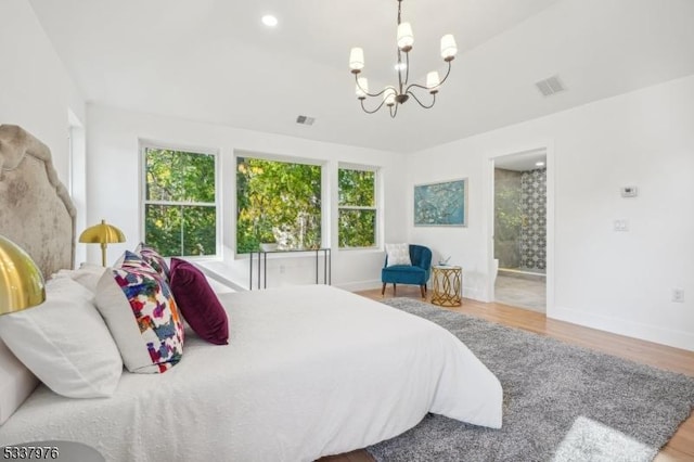 bedroom featuring an inviting chandelier, ensuite bathroom, and light hardwood / wood-style flooring