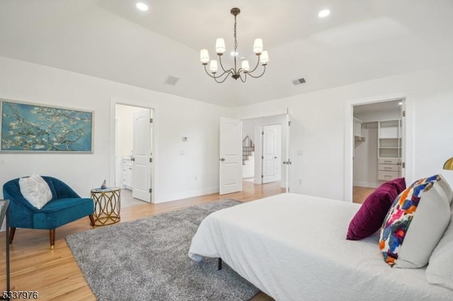 bedroom with a spacious closet, hardwood / wood-style floors, and a notable chandelier