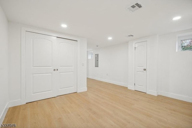 basement with light hardwood / wood-style floors and electric panel