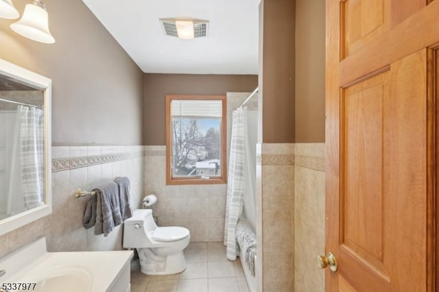 bathroom with walk in shower, tile patterned floors, toilet, tile walls, and vanity