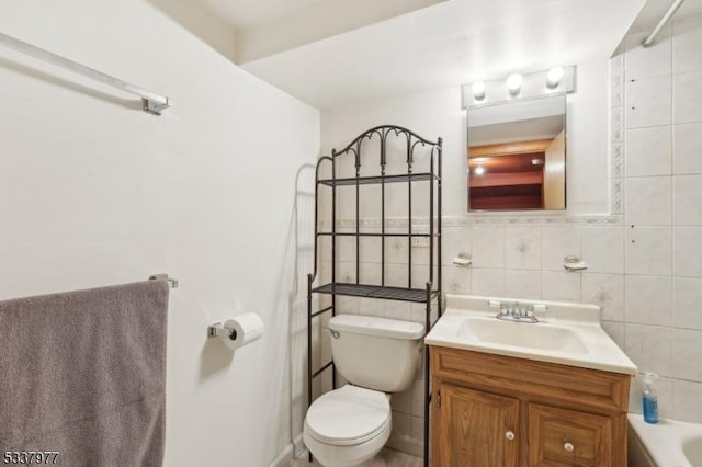 bathroom featuring tile walls, vanity, a bathing tub, and toilet