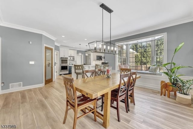 dining room featuring crown molding, visible vents, and light wood finished floors