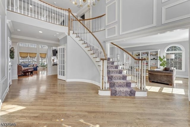 staircase with a wealth of natural light, wood finished floors, and ornamental molding