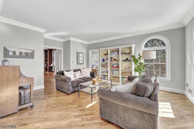 living room with crown molding, baseboards, and light wood-type flooring