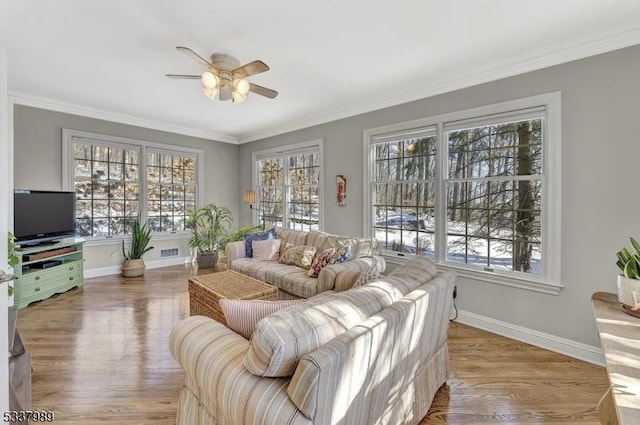 living area featuring crown molding, wood finished floors, baseboards, and ceiling fan