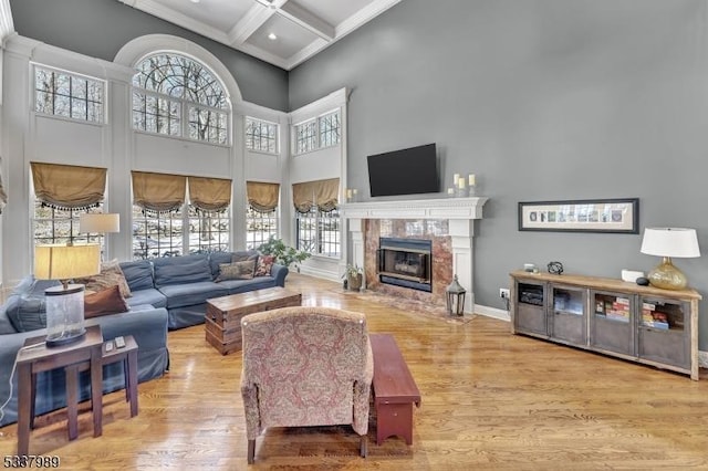 living room featuring a high end fireplace, baseboards, a high ceiling, wood finished floors, and coffered ceiling