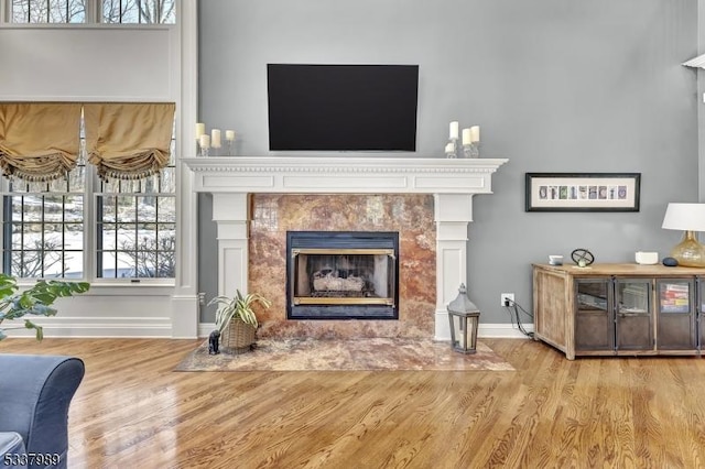 sitting room featuring wood finished floors, baseboards, and a high end fireplace