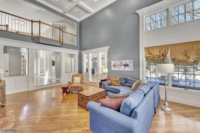 living room featuring ornate columns, light wood-style flooring, beamed ceiling, and coffered ceiling