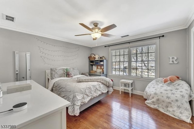 bedroom with visible vents, baseboards, crown molding, and hardwood / wood-style flooring