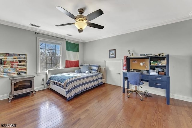 bedroom with visible vents, crown molding, and hardwood / wood-style floors