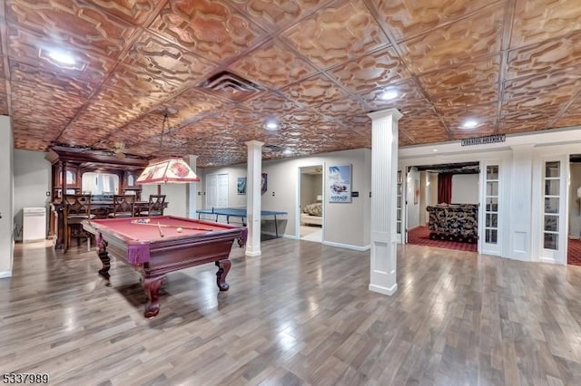 playroom featuring wood finished floors, visible vents, baseboards, decorative columns, and an ornate ceiling