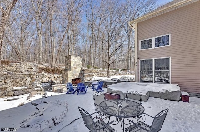 snow covered patio with a fireplace and outdoor dining area