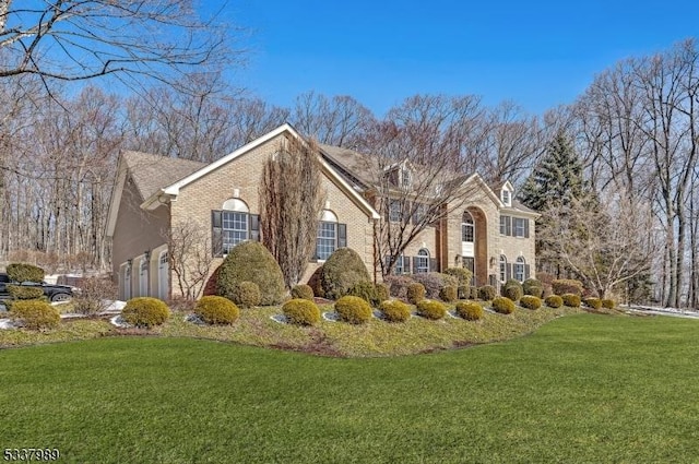 view of side of property featuring a yard, brick siding, and an attached garage