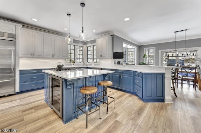 kitchen featuring blue cabinetry, stainless steel appliances, a peninsula, and light countertops