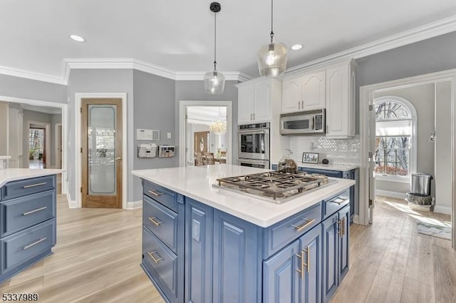 kitchen with blue cabinetry, appliances with stainless steel finishes, white cabinetry, and crown molding