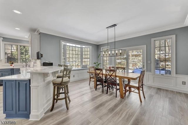 dining space with a healthy amount of sunlight, light wood-style flooring, and a decorative wall