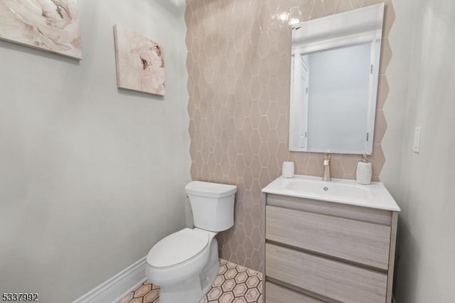 half bath featuring toilet, vanity, and baseboards