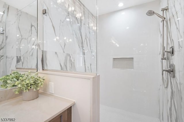 full bath featuring a marble finish shower and vanity