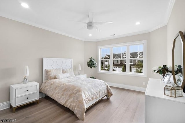 bedroom with crown molding, recessed lighting, wood finished floors, and baseboards