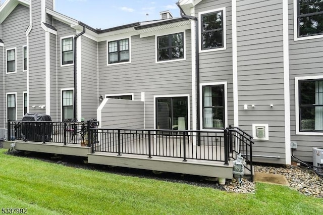 back of property featuring a lawn, a chimney, and a wooden deck