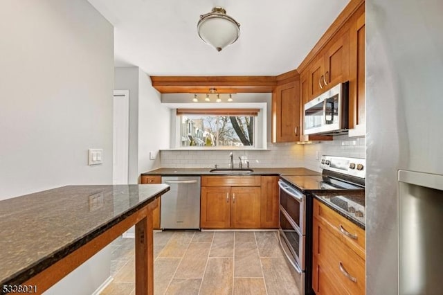 kitchen with appliances with stainless steel finishes, sink, dark stone countertops, and decorative backsplash