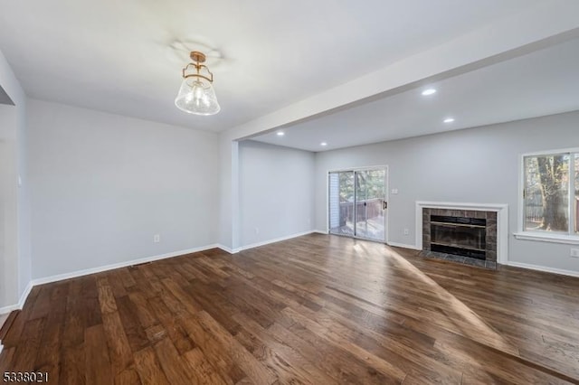 unfurnished living room featuring plenty of natural light, a tile fireplace, and dark hardwood / wood-style floors