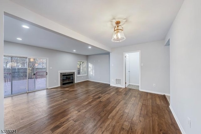 unfurnished living room featuring a tile fireplace and dark hardwood / wood-style floors