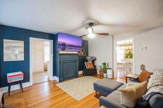 living room with ceiling fan, a fireplace, and light hardwood / wood-style floors