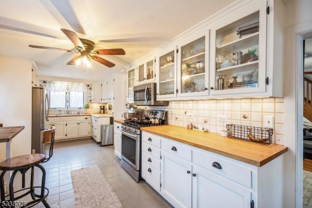 kitchen featuring white cabinetry, decorative backsplash, wooden counters, and appliances with stainless steel finishes