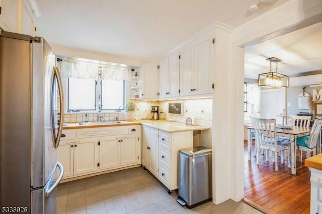 kitchen with hanging light fixtures, white cabinetry, and stainless steel refrigerator