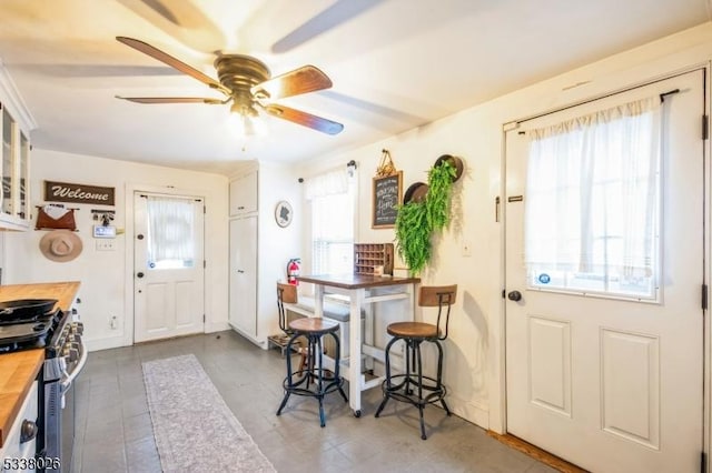 interior space featuring white cabinetry, stainless steel range with gas stovetop, ceiling fan, and butcher block countertops