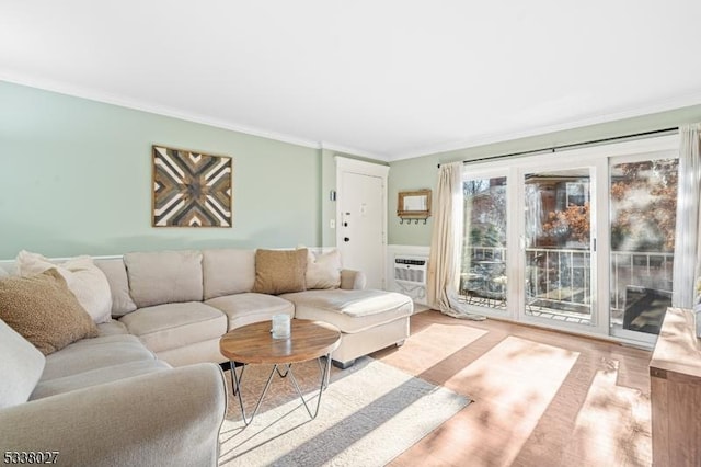 living room with crown molding, a wall unit AC, and light hardwood / wood-style flooring