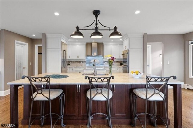 94 Brookville Hollow Rd, Delaware Twp, NJ 08559 - kitchen featuring wall chimney range hood, a sink, white cabinetry, baseboards, and wood finished floors