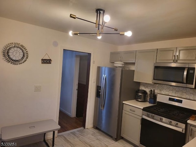 kitchen featuring stainless steel appliances, hanging light fixtures, decorative backsplash, and gray cabinetry