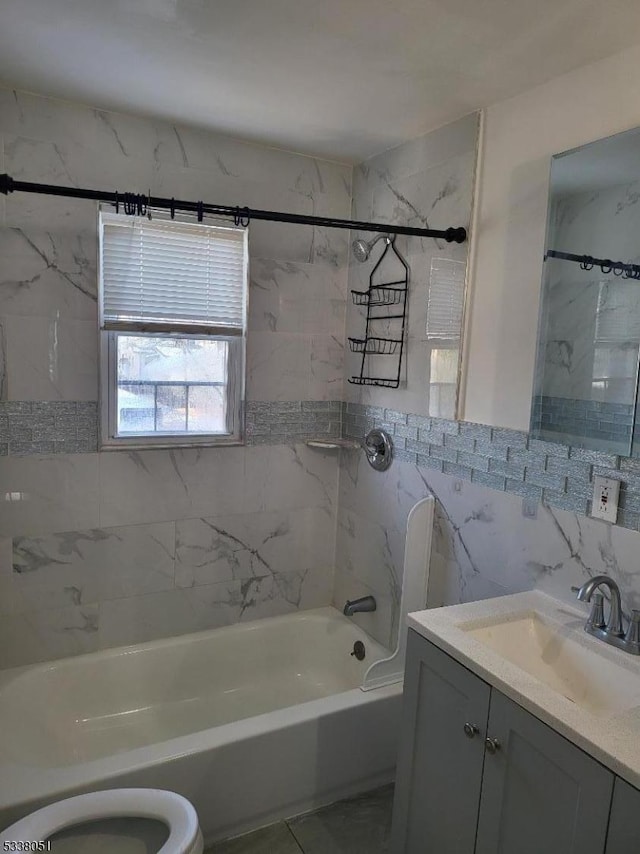 full bathroom featuring vanity, tiled shower / bath, tile walls, and toilet