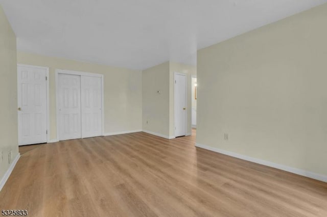 unfurnished bedroom featuring a closet, baseboards, and light wood finished floors