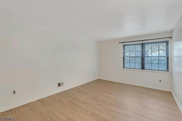 empty room with visible vents, baseboards, and light wood-style floors