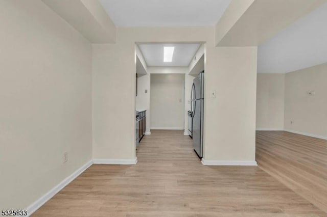 hall with light wood-style floors and baseboards