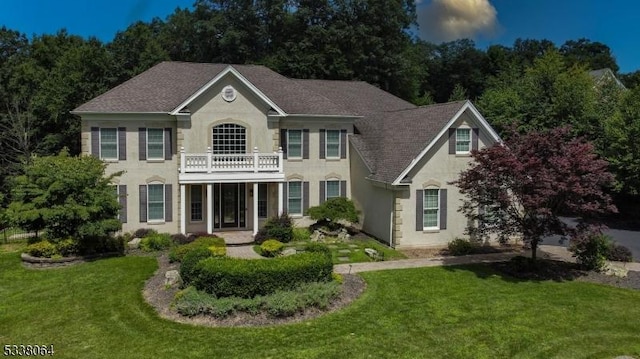 colonial home with a balcony and a front lawn