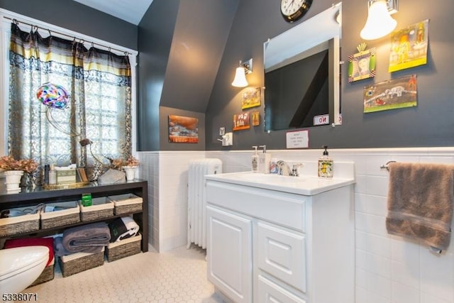 bathroom with vanity, radiator, toilet, and tile walls