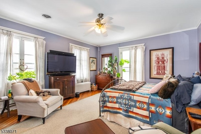 bedroom with radiator, crown molding, light hardwood / wood-style floors, and french doors