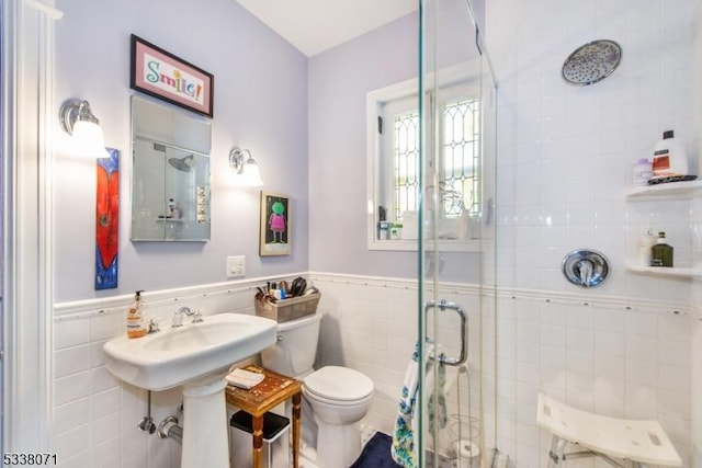 bathroom with toilet, an enclosed shower, and tile walls