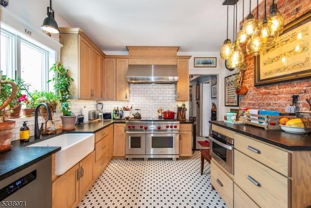 kitchen with appliances with stainless steel finishes, sink, wall chimney range hood, and decorative light fixtures