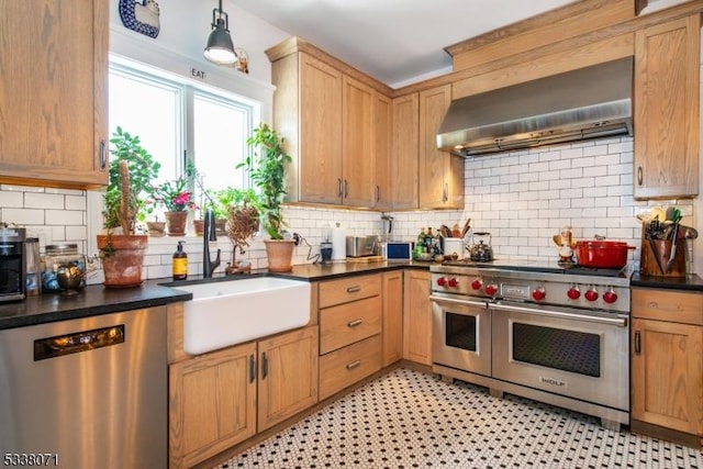 kitchen featuring wall chimney exhaust hood, sink, tasteful backsplash, decorative light fixtures, and stainless steel appliances