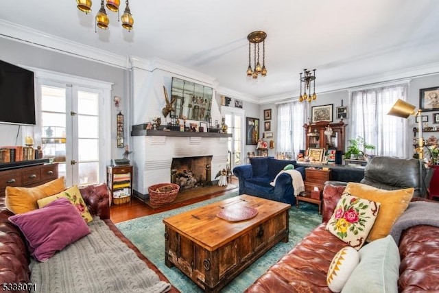 living room featuring crown molding, a large fireplace, hardwood / wood-style floors, and a notable chandelier