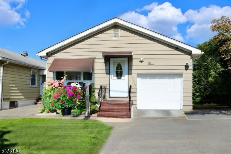 view of front of home featuring a front yard, driveway, an attached garage, and entry steps