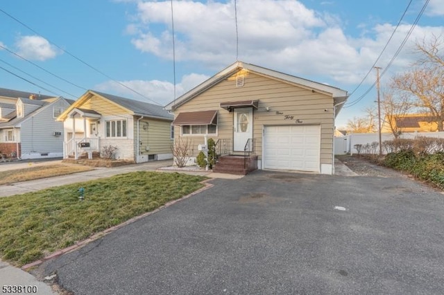 view of front of home featuring a garage, fence, and aphalt driveway