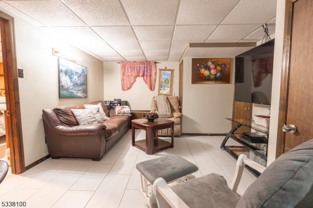 living area featuring light tile patterned floors, a paneled ceiling, and baseboards