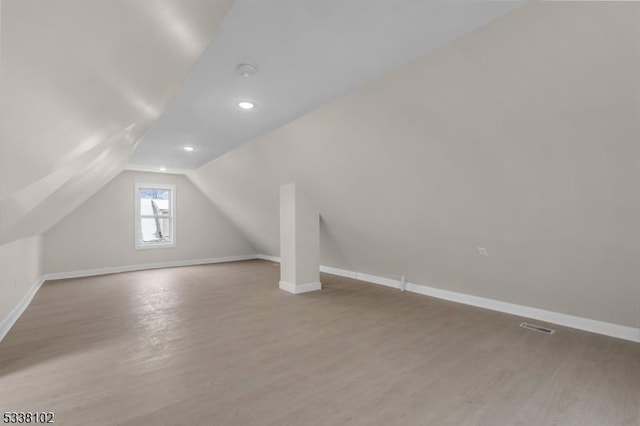 additional living space featuring vaulted ceiling and light hardwood / wood-style floors